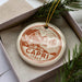 A decorative ornament in a box, featuring a circular design with a coastal scene and the text "CAPRI ITALY".