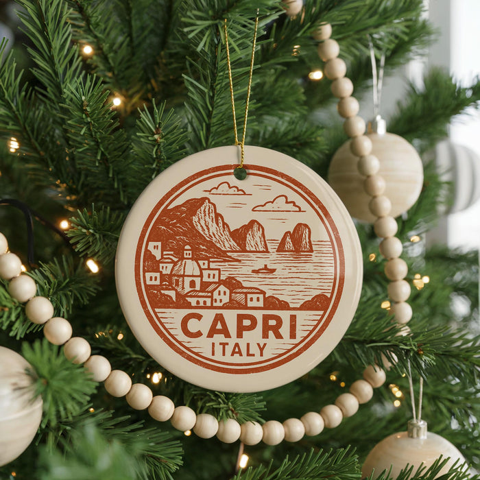 A Christmas tree decorated with ornaments, including a circular ornament with a design of a coastal town and mountains, and a beaded ornament.
