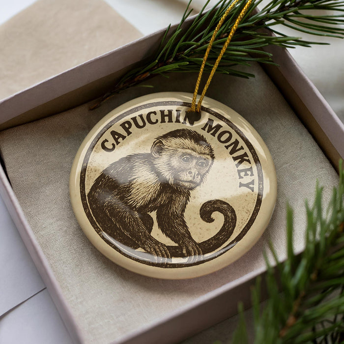 A decorative ornament featuring a monkey is displayed in a box, surrounded by pine branches.
