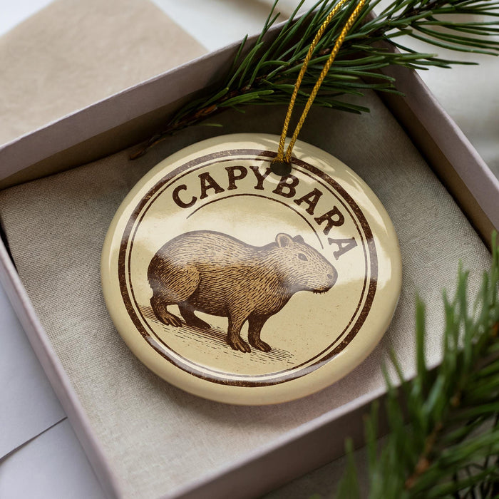 A round ornament with the word "CAPYBARA" printed on it, featuring an illustration of a rodent.