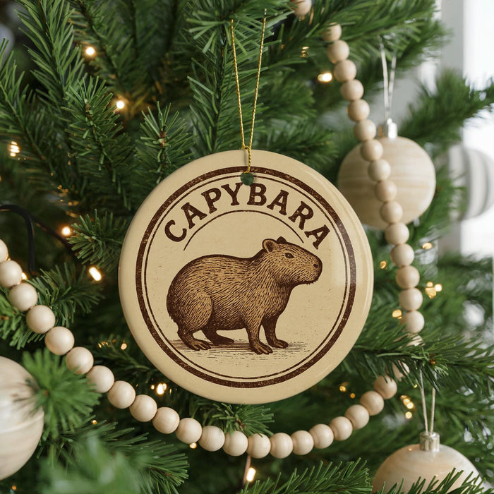 A Christmas tree decorated with ornaments, including a circular ornament with a picture of a capybara and the word "CAPYBARA" written on it.