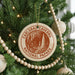 A Christmas tree decorated with ornaments, including a circular ornament with the text "CARLSBAD CAVENS NATIONAL PAPARK" and a beaded ornament.