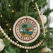 A round ornament on a Christmas tree, featuring a palm tree and beach scene with the text "CAVE CAULKER BELIZE" around the edge.