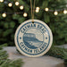 A circular ornament with the text " Cayman Brac Cayman Islands" printed on it, hanging from a string.