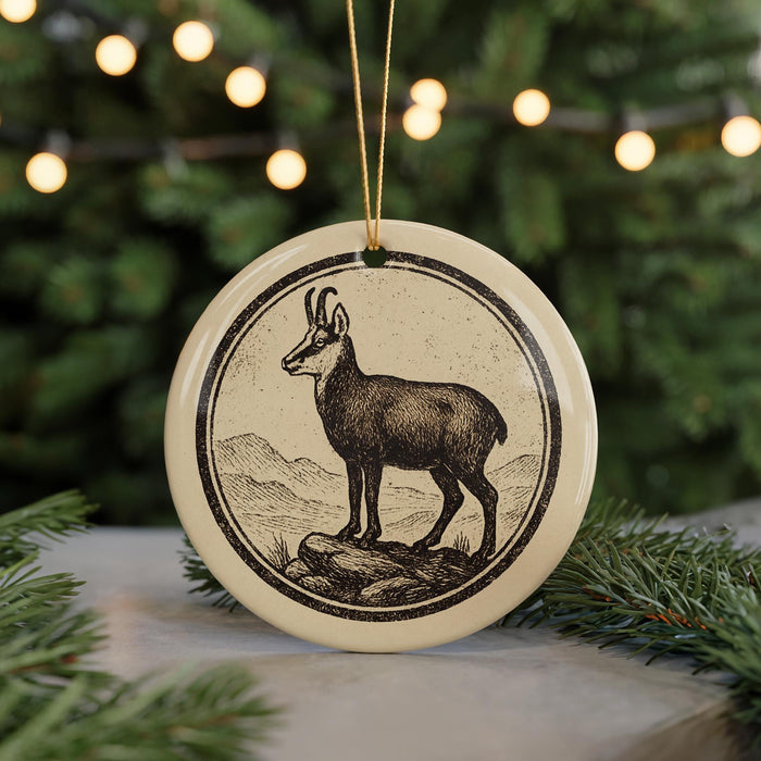 A round ornament featuring a black and white illustration of a mountain goat standing on a rock.