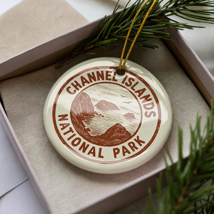 A round ornament with the text "CHANNEL ISLANDS NATIONAL PARK" printed on it, placed in a box with pine branches.
