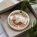 A round ornament with the text "CHANNEL ISLANDS NATIONAL PARK" printed on it, placed in a box with pine branches.