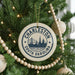 A Christmas tree decorated with ornaments, including a circular ornament with the text "CHARLESTON SOUTH OREGON" and a suspension bridge design.
