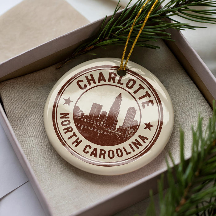 A circular ornament with the text "CHARLOTTE NORTH CAROLINA" printed on it, surrounded by pine branches.