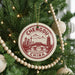 A Christmas tree decorated with ornaments, including a circular ornament with a design of a city skyline and mountains, and a beaded ornament.