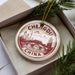A decorative ornament in a box, featuring a circular design with a cityscape and mountains, along with the text "CHENGDU CHINA".