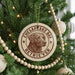 A Christmas tree decorated with ornaments, including a circular ornament with a brown and white design featuring a dog's head and the text "CHESAPKE BAY RETRIEVER".