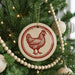 A Christmas tree decorated with ornaments, including a circular ornament featuring a red rooster design.