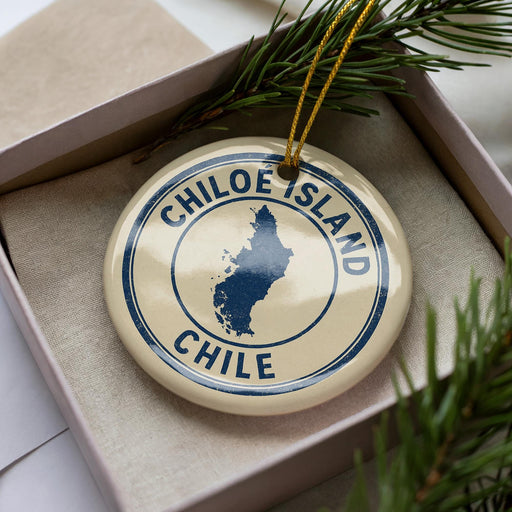 A circular ornament with the text "CHILIE" and a map of Chile, placed inside a box with pine branches.