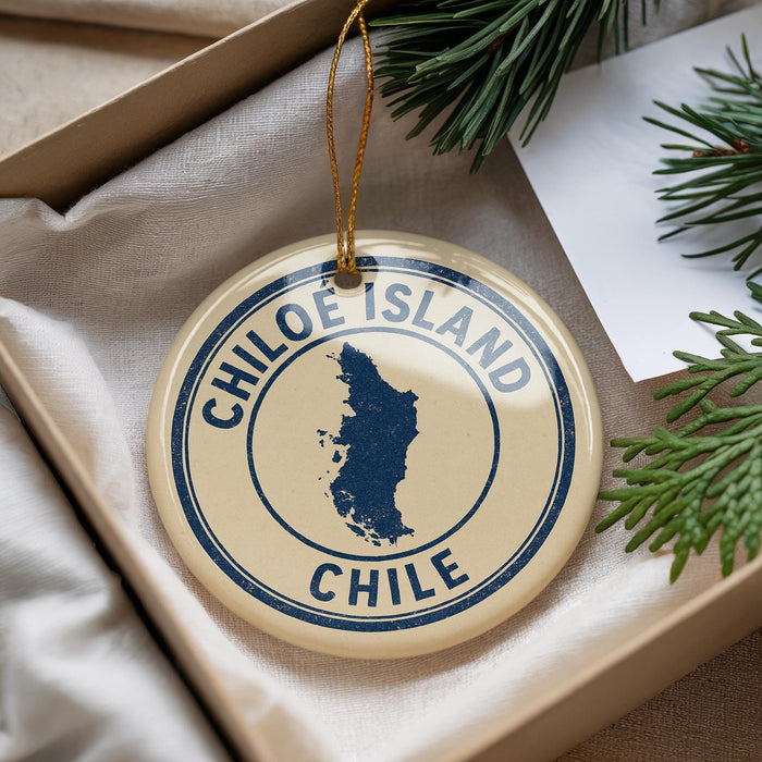A decorative ornament with the text "CHILE" and a map of Chile, placed in a box with pine branches.