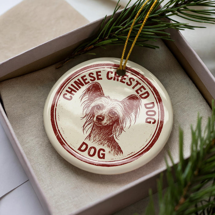 A decorative ornament in a box, featuring a Chinese crested dog's head and the text "CHINESE CREsted DOG DOG" printed on it.