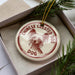 A decorative ornament in a box, featuring a Chinese crested dog's head and the text "CHINESE CREsted DOG DOG" printed on it.
