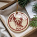A round ornament with a dog image and the text "CHINESE CREED DOG DOG" printed on it, hanging from a string.