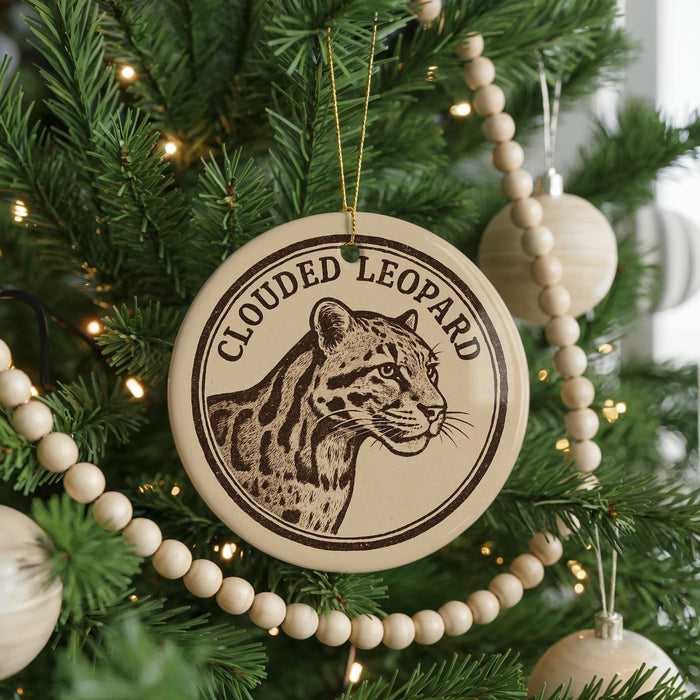 A Christmas tree decorated with ornaments, including a circular ornament featuring a leopard's face and the text "CLOUDED LEOPARD".
