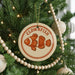 A Christmas tree decorated with ornaments, including a round ornament with an image of a clownfish and the word "CLOWNSFISH" written on it.