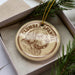 A round ornament featuring a Clumber Spaniel dog, with the text "CLUMBER SPANIEL" printed on it, is displayed in a box surrounded by pine branches.