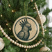 A Christmas tree decorated with ornaments, including a circular ornament featuring a black and white illustration of a parrot.