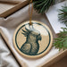 A decorative ornament featuring a parrot is displayed in a box, surrounded by pine branches.