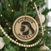 A round ornament with a monkey's face on it, hanging from a Christmas tree.