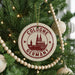 A Christmas tree decorated with ornaments, including a circular ornament with the text "COLOGNE GERMANY" and a castle illustration.