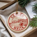 A circular ornament with the text "COMINO MALTA" printed on it, hanging from a string.