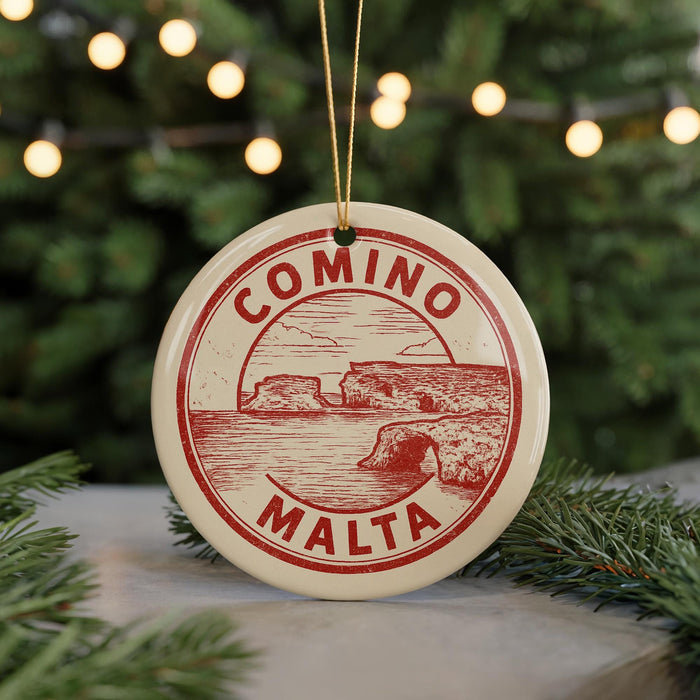 A circular ornament with the text "COMINO MALTA" printed on it, hanging from a string.