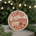 A circular ornament with the text "COMINO MALTA" printed on it, hanging from a string.