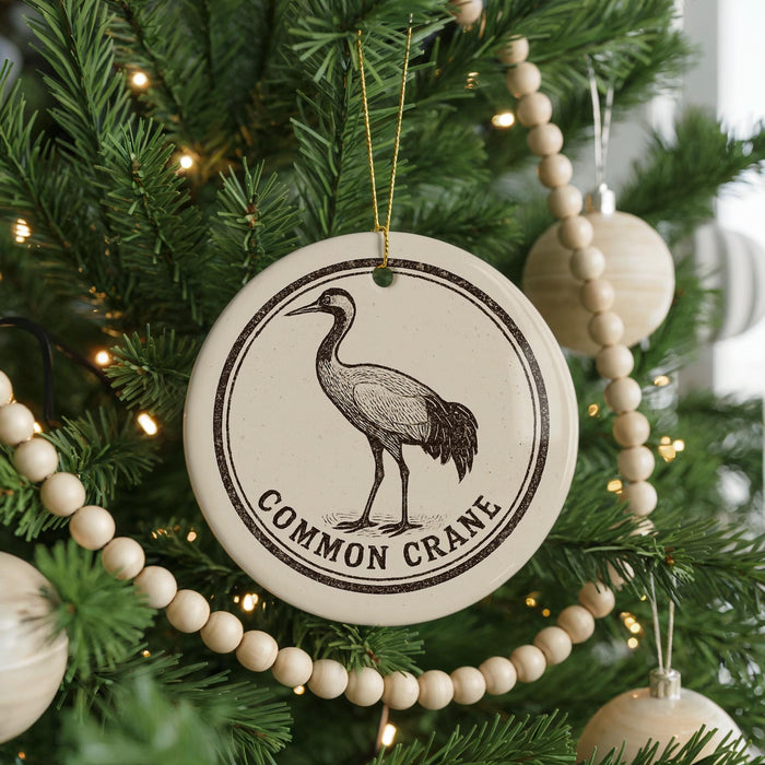 A Christmas tree decorated with ornaments, including a circular ornament featuring a black and white illustration of a crane and the text "Common Crane".