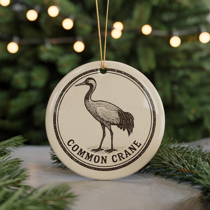 A circular ornament featuring a black and white illustration of a crane, with the text "COMMON CRANE" printed on it, hanging from a string.