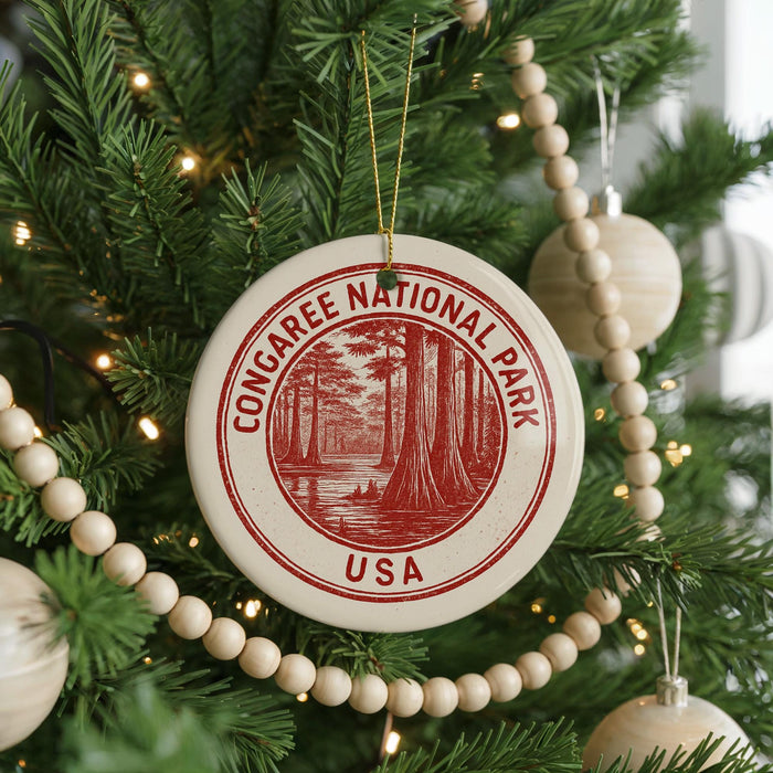 A Christmas tree decorated with ornaments, including a circular ornament with the text "CONGAREE NATIONAL PARK USA" and a tree with white beads.