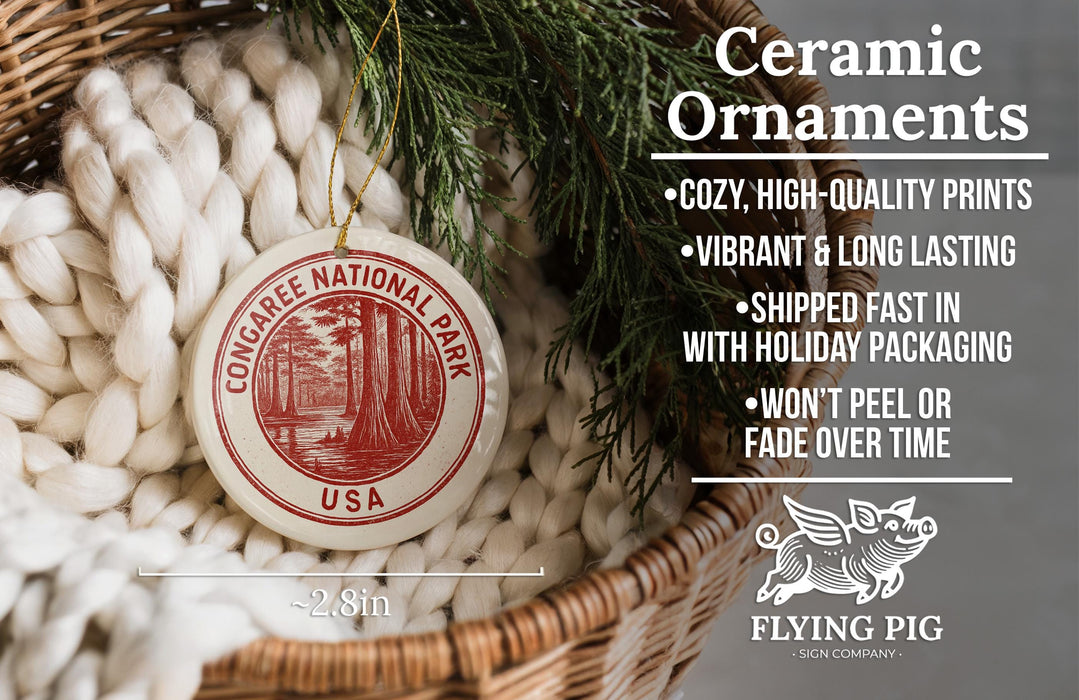 Ceramic ornaments, featuring a red and white design with the text "CONGAREE NATIONAL PARK USA" and a bird illustration, are displayed in a woven basket.