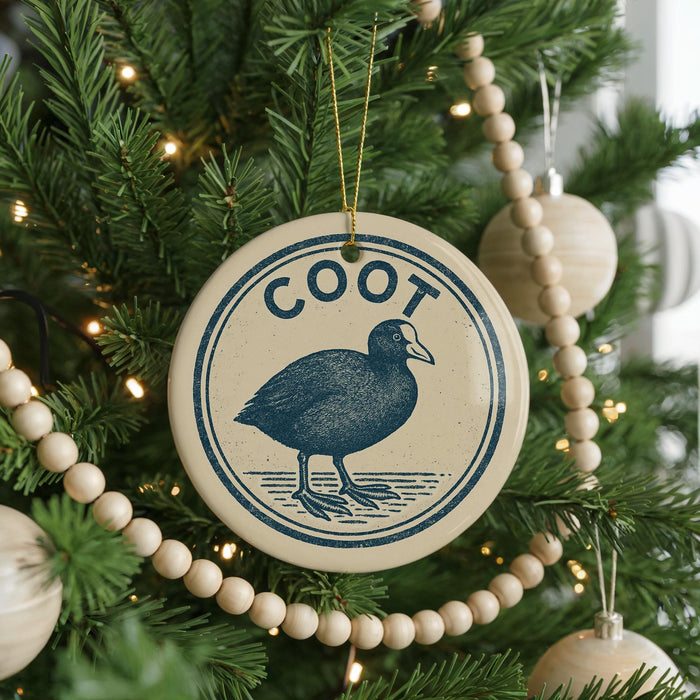 A Christmas tree decorated with ornaments, including a circular ornament with a bird image and the word "Coot" written on it.