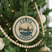 A round ornament on a Christmas tree with the text "CORFU GREECE" and a graphic of a building and a mountain.