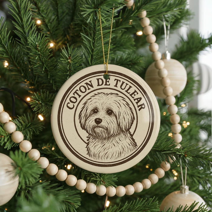 A round ornament with a dog's face on it, hanging from a Christmas tree.