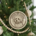 A round ornament with a dog's face on it, hanging from a Christmas tree.