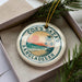 A circular ornament with a tropical beach scene and palm trees, featuring the text "COX'S BAZAR BANGLADESH" on it.