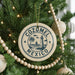 A Christmas tree decorated with ornaments, including a circular ornament with the text "COZUMEL MEXICO" and a lighthouse illustration.