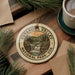 A decorative ornament featuring the image of the Cuyahoga Valley National Park in the United States, surrounded by pine branches and a cup of coffee.
