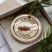 A circular ornament with the text "CYPRUS" and a map of the island of Cyprus, surrounded by pine branches.