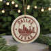 A circular ornament with the text "DALLAS TEXAS" and a silhouette of a city skyline, hanging from a string.