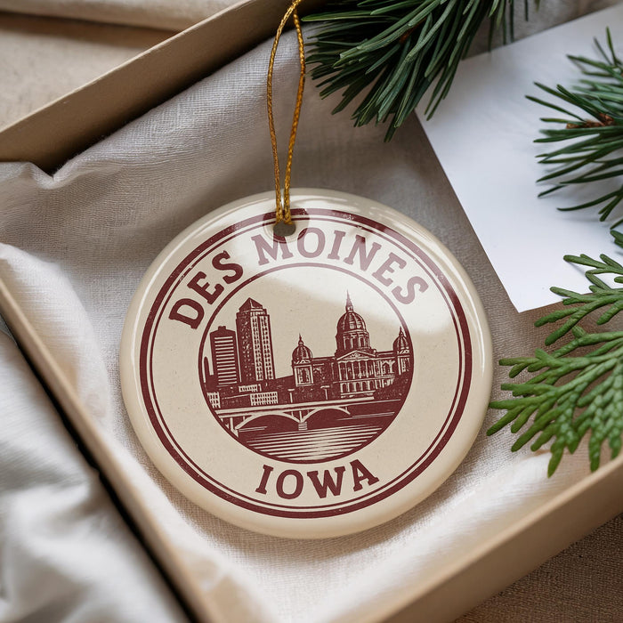 A decorative ornament with the text "DES MOINES IOWA" and an illustration of a city skyline, hanging from a string.