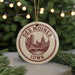 A circular ornament with the text "DES MOINES IOWA" and an illustration of a city skyline, hanging from a string.