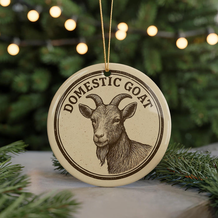 A round ornament with a goat's head and horns, surrounded by a decorative border, is displayed in front of a Christmas tree with twinkling lights.