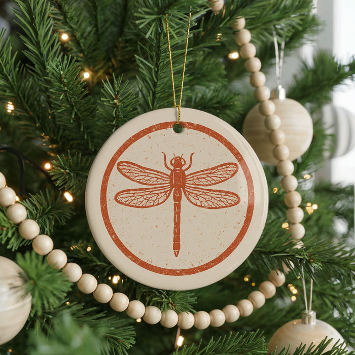 A Christmas tree decorated with ornaments, including a circular ornament featuring a dragonfly design.
