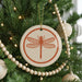 A Christmas tree decorated with ornaments, including a circular ornament featuring a dragonfly design.